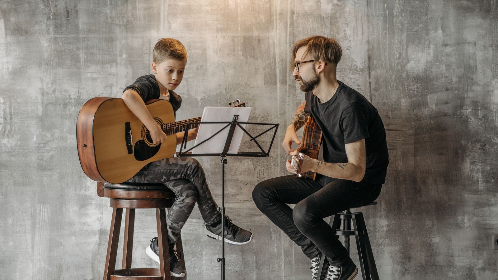 Aluna iniciante em aula de violino com o professor corrigindo a posição do arco