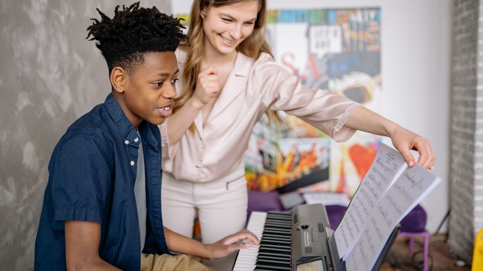 Aluna em aula de canto ao lado do piano com o professor orientando a respiração