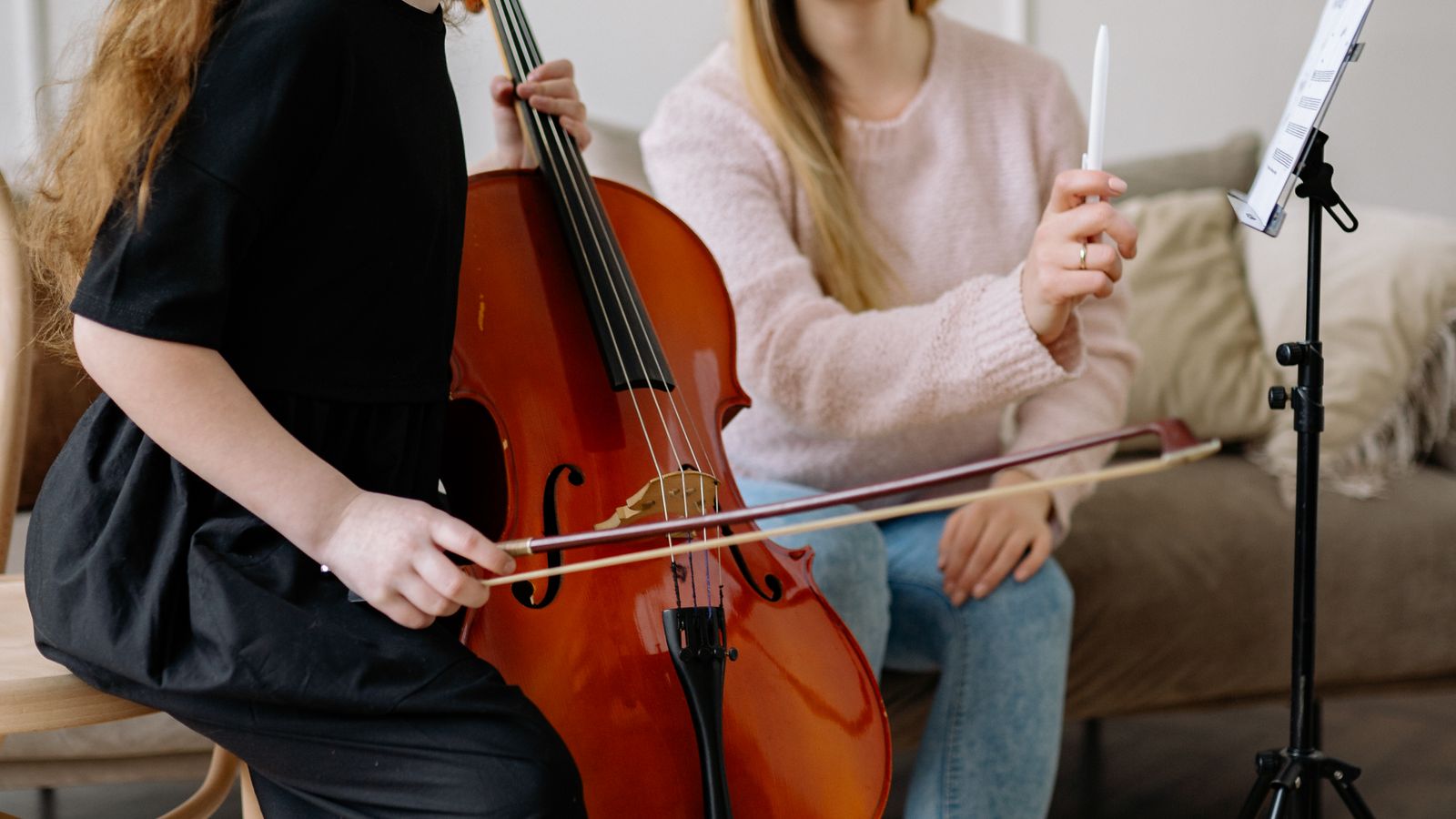 Aluno tocando guitarra elétrica em aula com o professor corrigindo a posição da mão
